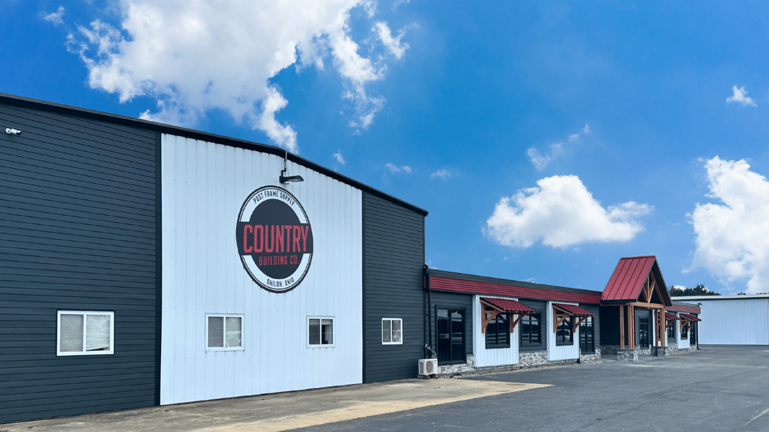 Country Building Co. storefront in Shiloh, Ohio with a black-and-white exterior and red awnings under a blue sky.