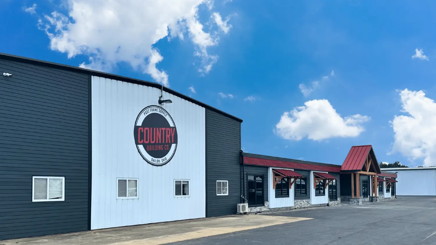 Country Building Co. storefront in Shiloh, Ohio with a black-and-white exterior and red awnings under a blue sky.